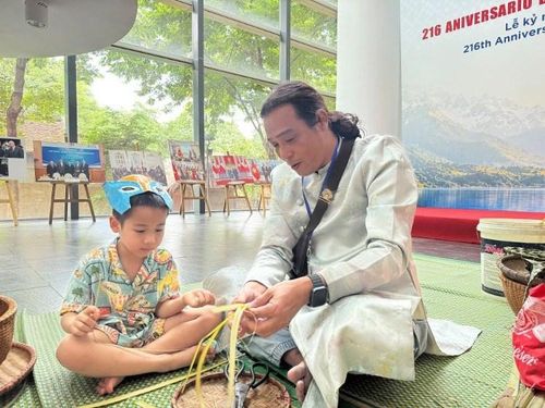 Nghệ nhân hướng dẫn em nhỏ làm đồ chơi bắng tết lá tại Bảo tàng Dân tộc học Việt Nam