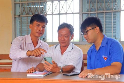 Đảng viên trẻ, Chi bộ ấp Mỹ Long 4, xã Mỹ Hiệp hướng dẫn ông Trần Quốc Khải sử dụng Sổ tay đảng viên điện tử, chủ động tiếp cận tài liệu trên nền tảng số.