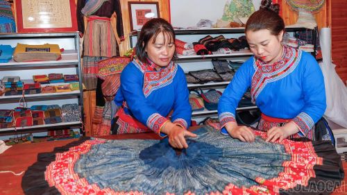 Chị Ly Thị Rua và chị Sùng Thị Xoa sắp xếp lại những bộ trang phục Mông Hoa rực rỡ, được may từ vải thổ cẩm kết hợp với hoa văn truyền thống, để bán và cho du khách thuê chụp ảnh.