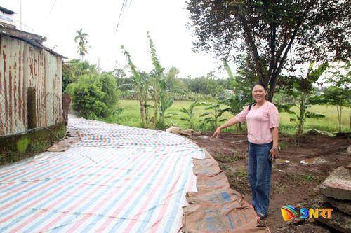 Bà Nguyễn Thị Kim Mai bên đường dân sinh vừa thảm bê tông. Ảnh: HÀN NGUYÊN