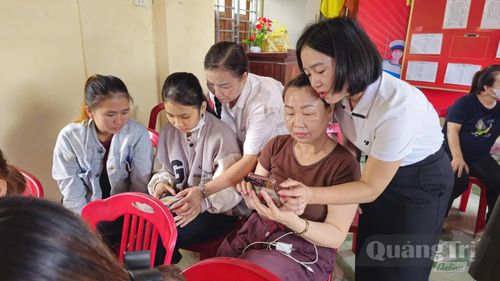 Cán bộ Trung tâm Phục vụ hành chính công xã Cửa Việt hướng dẫn người dân thôn Xuân Hoàng thực hiện thủ tục hành chính trên điện thoại thông minh - Ảnh: N.T.H