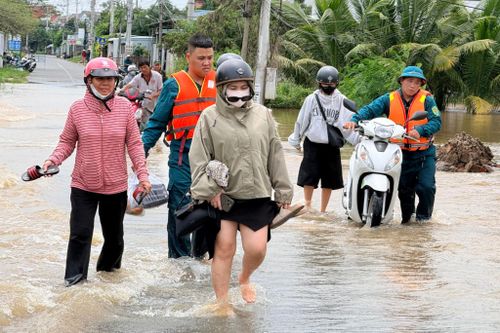 Lực lượng dân quân hỗ trợ người dân đi qua đoạn đường bị ngập và chảy xiết.