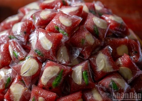 Sau khi được để lên bề mặt lá vông, người làm nhấn hạt tiêu, trái ớt và một lát tỏi vào sao cho hỗn hợp nem nằm gọn, không bị lộ ra ngoài.
