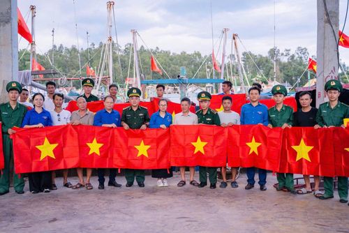 Tuổi trẻ Đồn Biên phòng Quỳnh Thuận, Bộ đội Biên phòng tỉnh Nghệ An phối hợp đoàn viên thanh địa phương trao tặng cờ Tổ quốc cho ngư dân. (Ảnh: LÊ THẠCH)