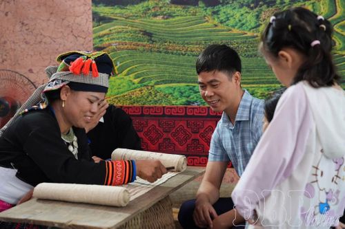 Du khách thích thú tìm hiểu kỹ thuật vẽ hoa văn bằng sáp ong trên vải lanh của phụ nữ Mông, thêm những trải nghiệm gần gũi, đáng nhớ tại ngày hội.