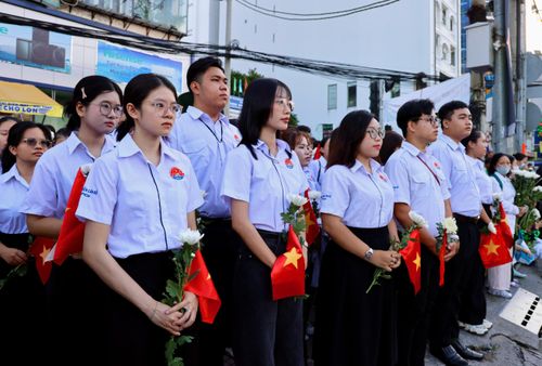  Sinh viên Học viện Cán bộ TPHCM chờ tiễn đoàn xe đưa hài cốt liệt sĩ trên đường Cách Mạng Tháng Tám, phía trước Công viên Lê Thị Riêng. Ảnh: HOÀNG TRIỀU 
