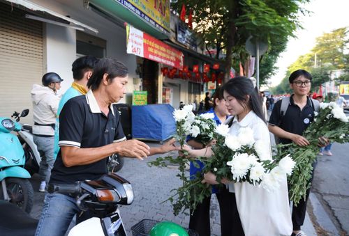  Những nhành cúc trắng được trao tặng người dân trước Công viên Lê Thị Riêng để tiễn đưa các Anh hùng liệt sĩ về nơi an nghỉ. Ảnh: HOÀNG TRIỀU 