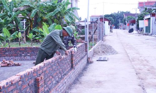 Người dân thôn Đông La, xã Trung Chính xây dựng lại tường rào sau khi hiến đất mở rộng đường.