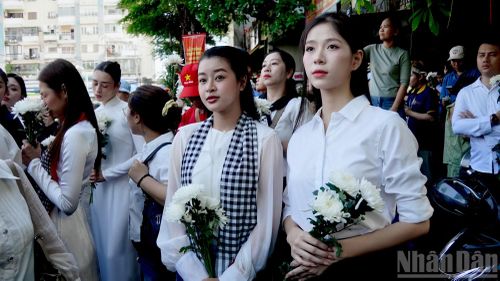 Các bạn trẻ chờ tiễn đưa hài cốt liệt sĩ trước khu vực cổng Công viên Văn hóa Lê Thị Riêng. (Ảnh: Báo Nhân dân)
