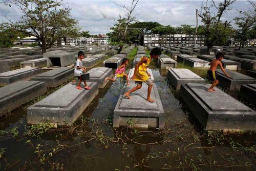Ảnh ấn tượng trong tuần: Trẻ em Philippines nhảy trên những ngôi mộ bị ngập lụt