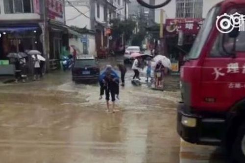 Cụ ông cõng vợ lội qua vũng nước