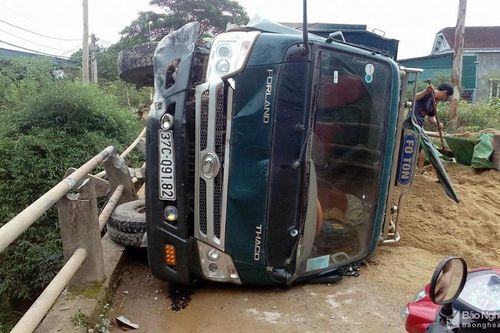 Xe tải lật ngang giữa cầu, dân trèo cabin kéo tài xế ra ngoài
