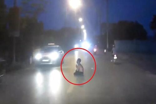 Người đàn ông cởi trần, chắp tay ngồi giữa đường