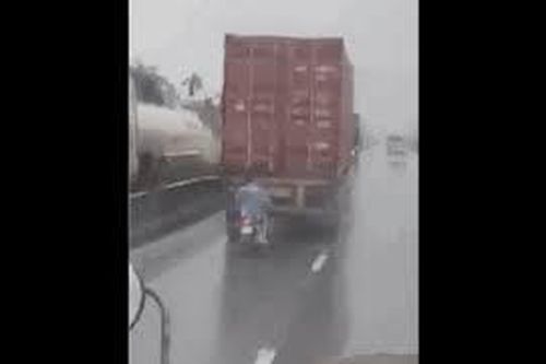 Điều khiển xe máy chạy bám đuôi xe công-ten-nơ để... trú mưa