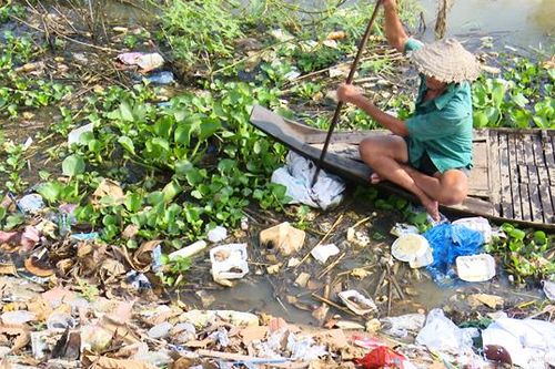 Lão nông cần mẫn làm sạch môi trường nước mùa lũ