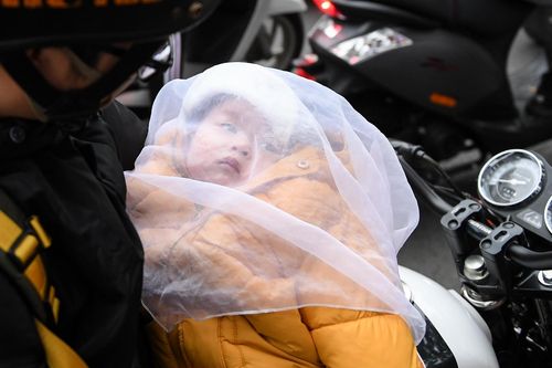Bế con ngồi ngoài đường chờ vợ mua quần áo giảm giá dịp Tết