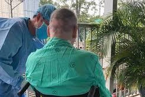 Bệnh nhân COVID-19 là phi công người Anh ngồi xe lăn phơi nắng, tự cầm bút viết bảng