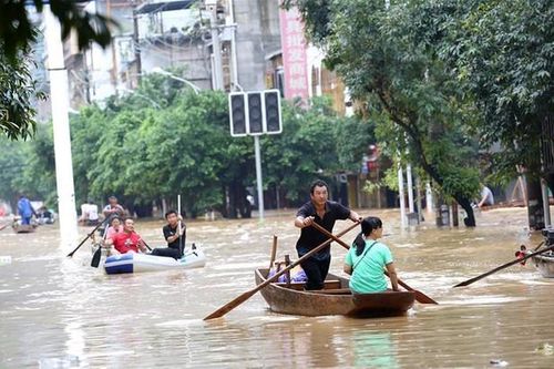 Lũ lụt dâng cao, người dân chèo thuyền đi lại trên phố