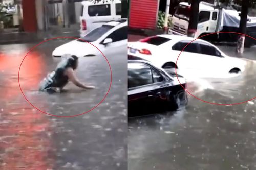 Người phụ nữ bơi trên đường bị ngập suýt bị ôtô đâm trúng