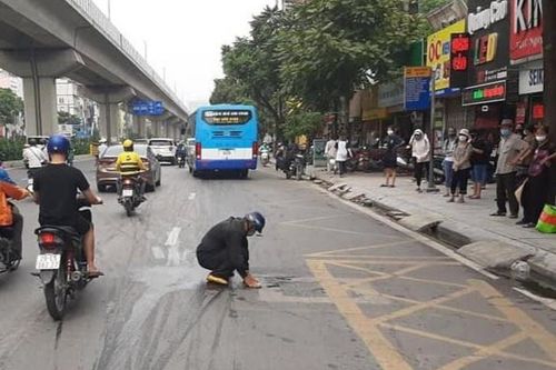 Người đàn ông dọn vết dầu thải bị đổ giữa đường