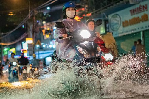 Người dân TP.HCM lội nước về nhà sau mưa lớn