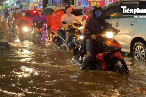 Người dân Sài Gòn lại bì bõm dắt xe lội nước về nhà sau cơn mưa lớn