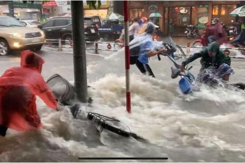 Bất chấp dòng nước chảy xiết do mưa lớn để đạp xe về nhà, nhóm học sinh ngã nhào xuống đường khiến nhiều người thót tim