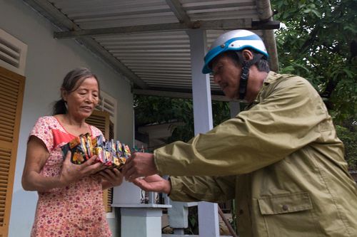 Cán bộ chèo ghe đến vùng lũ phát mì tôm cho dân