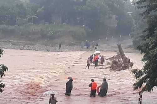Lực lượng biên phòng cùng người dân đưa sản phụ qua cầu tràn ngập nước lũ đi sinh