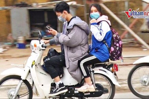 Học sinh đầu không mũ BH, tay lướt điện thoại phóng xe vun vút đến trường