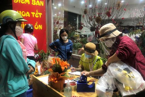 Nhân viên đội mũ chống giọt bắn bán hoa đại hạ giá ở TP.HCM
