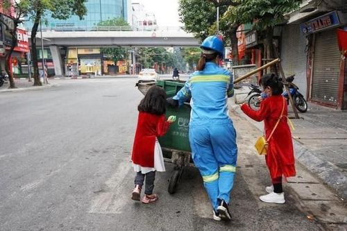 Bức ảnh 2 bé gái diện áo dài, phụ mẹ làm lao công đẩy xe rác trên phố gây xúc động