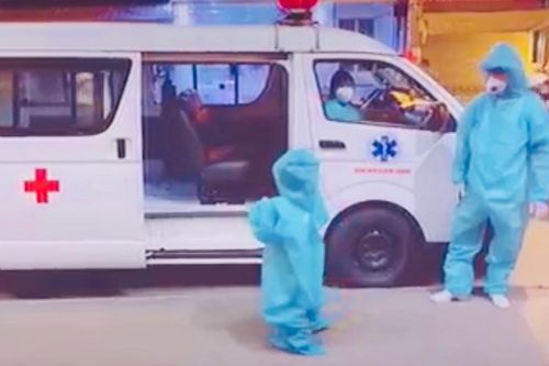Bé 5 tuổi trong trang phục bảo hộ rộng thùng thình, tự giác leo lên xe cấp cứu đi điều trị COVID-19