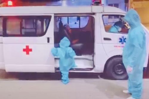 Bé 5 tuổi trong trang phục bảo hộ rộng thùng thình, tự giác leo lên xe cấp cứu đi điều trị COVID-19