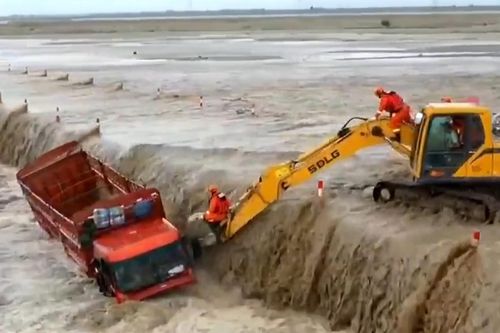 Dùng máy xúc để giải cứu tài xế bị kẹt giữa dòng nước lũ
