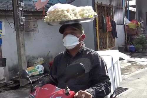 Người bán hàng ở Thái Lan đội khay măng cụt khi đi xe máy