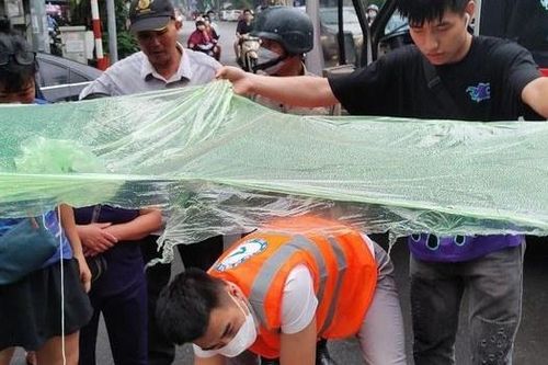 Nhiều người dân che mưa cho nạn nhân vụ tai nạn giao thông