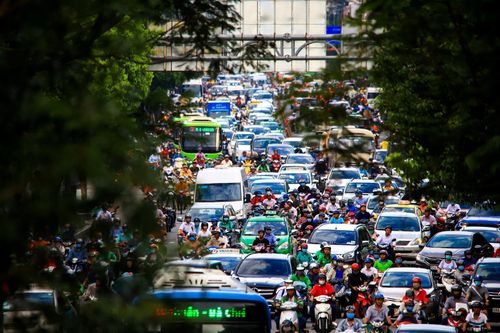 Người đi bộ kẹt giữa dòng xe dưới các cao ốc ở TP.HCM