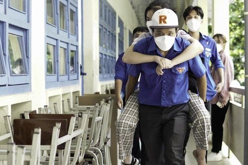 Tình nguyện viên cõng thí sinh bị gãy chân, ngồi xe lăn vào phòng thi