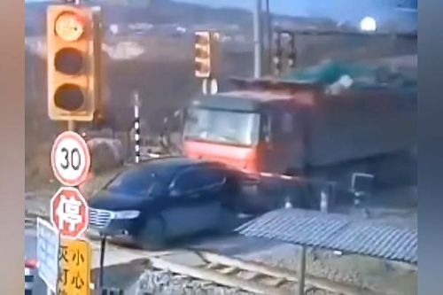 Hãi hùng cảnh xe tải từ từ ủi ô tô con lên đường sắt khi tàu hỏa sắp đến
