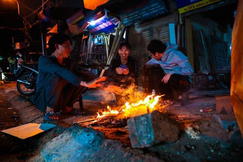 Nhiệt độ xuống thấp 12 độ C, người dân đốt lửa sưởi ấm trên vỉa hè ở Hà Nội