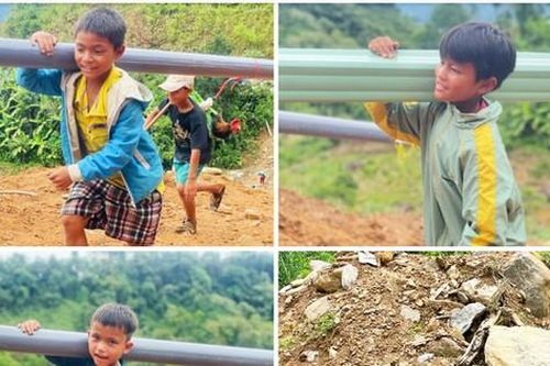 Thanh niên cùng người dân lội bộ đường rừng cõng vật liệu về làng