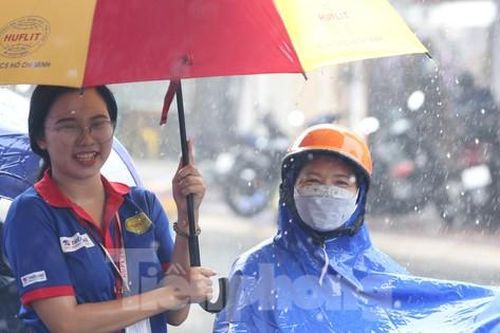 Tình nguyện viên đội mưa che ô cho thí sinh và phụ huynh