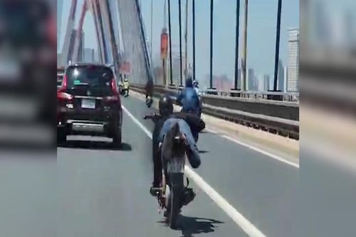 Nam thanh niên nằm trên yên xe máy phóng vun vút qua cầu Nhật Tân