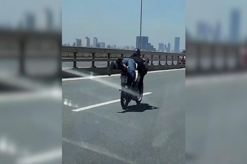 Nam thanh niên nằm trên yên xe máy phóng vun vút qua cầu Nhật Tân