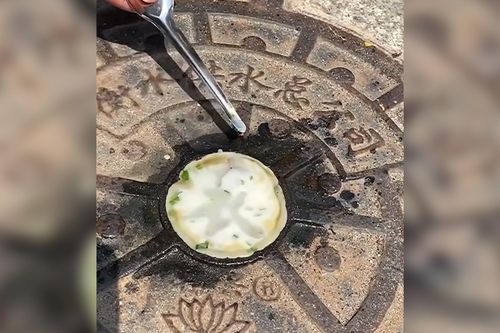 Người đàn ông nướng bánh trên nắp cống giữa nắng nóng như thiêu đốt