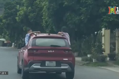 Hai trẻ nhỏ thò người ra khỏi cửa xe đang chạy