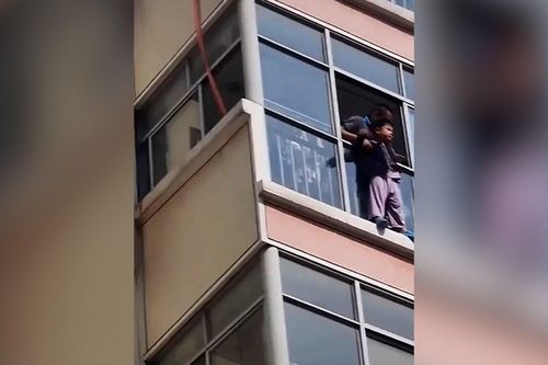 Người đàn ông đu dây cứu cậu bé mắc kẹt ở cửa sổ