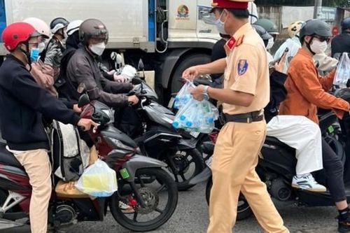 Cảnh sát giao thông phát nước, khăn lạnh cho người dân về quê đón Tết