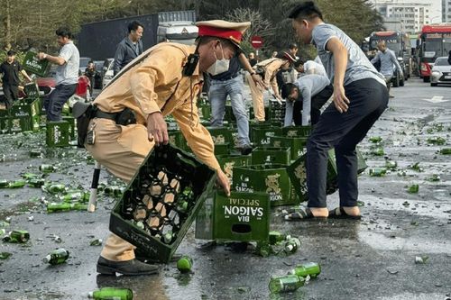 Cảnh sát giao thông cùng người dân thu dọn hàng trăm thùng bia rơi xuống đường